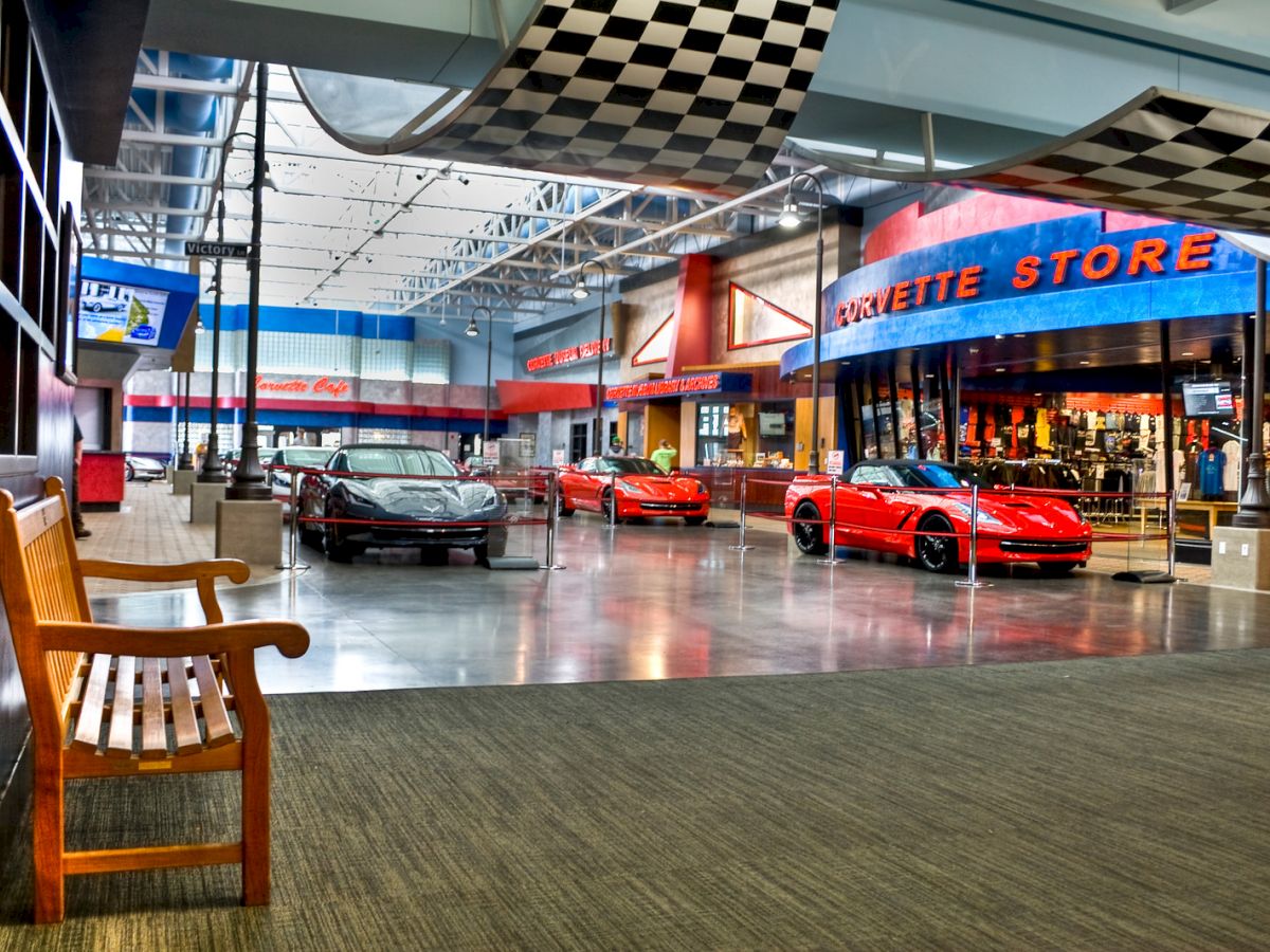 An indoor showroom displays red sports cars, next to a store labeled "Corvette Store" with checkered flag decor.