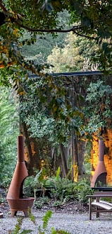 A mirrored structure reflecting trees and greenery in a forested area, blending seamlessly with the natural surroundings.
