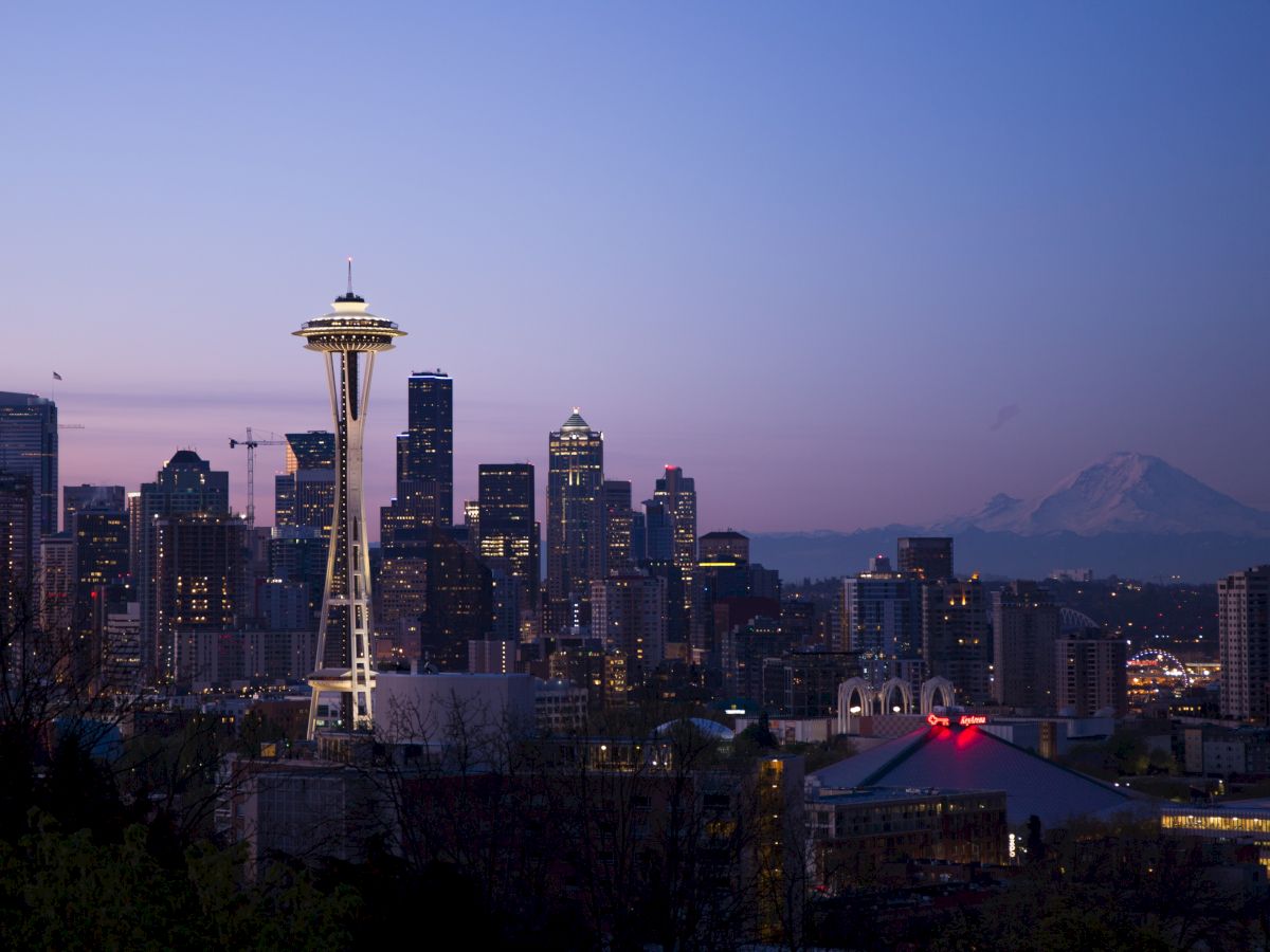 This image shows the Seattle skyline during twilight, with the Space Needle prominently featured and Mount Rainier visible in the background.