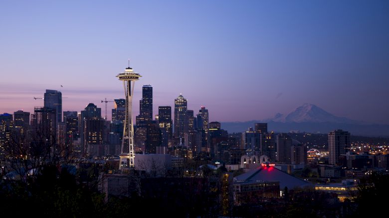 This image shows the Seattle skyline during twilight, with the Space Needle prominently featured and Mount Rainier visible in the background.
