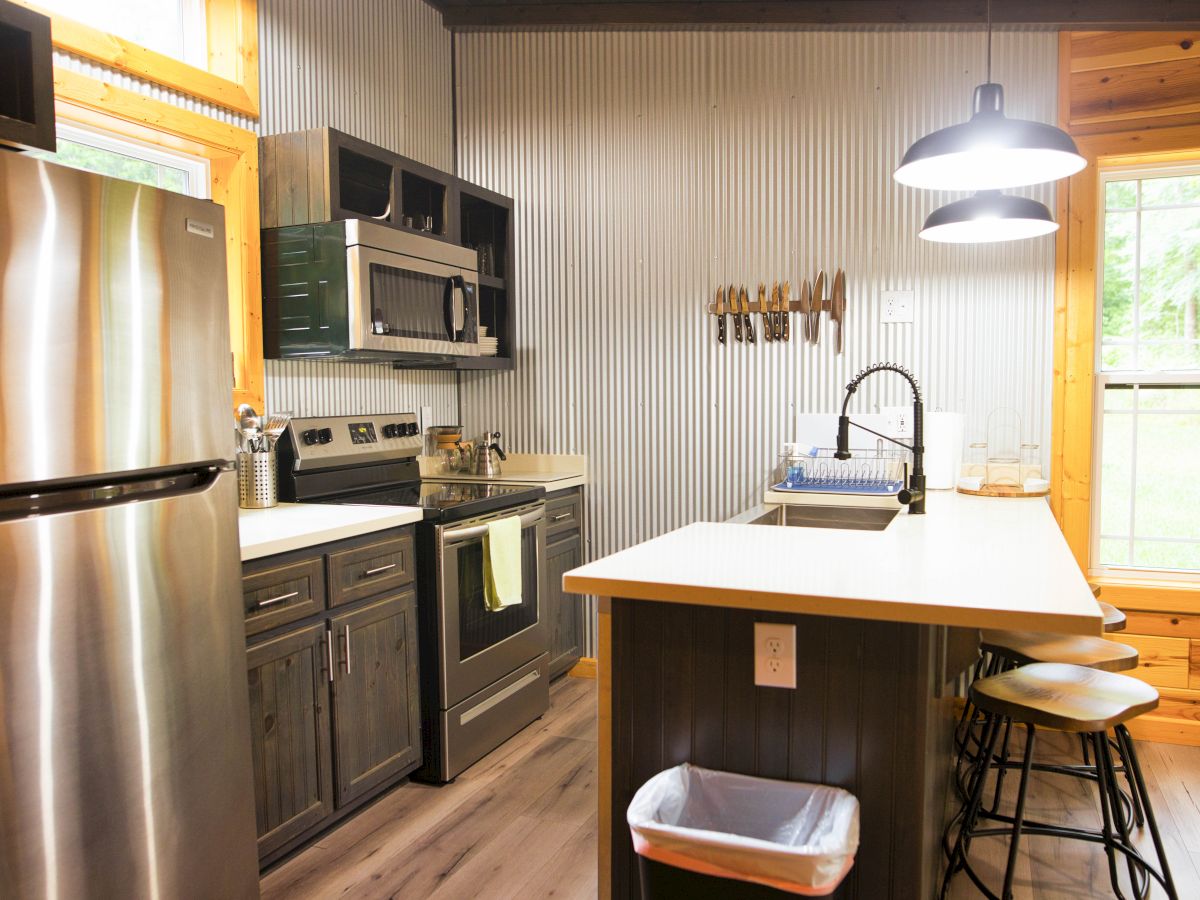 A modern kitchen with stainless steel appliances, an island with stools, and large windows providing natural light ends the formal description.