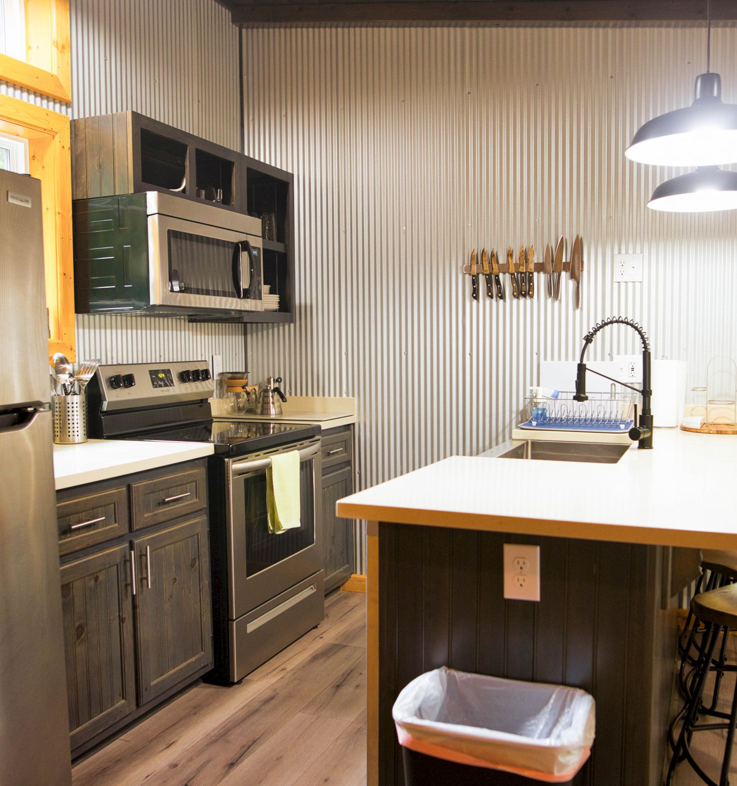 A modern kitchen with stainless steel appliances, an island with stools, and large windows providing natural light ends the formal description.