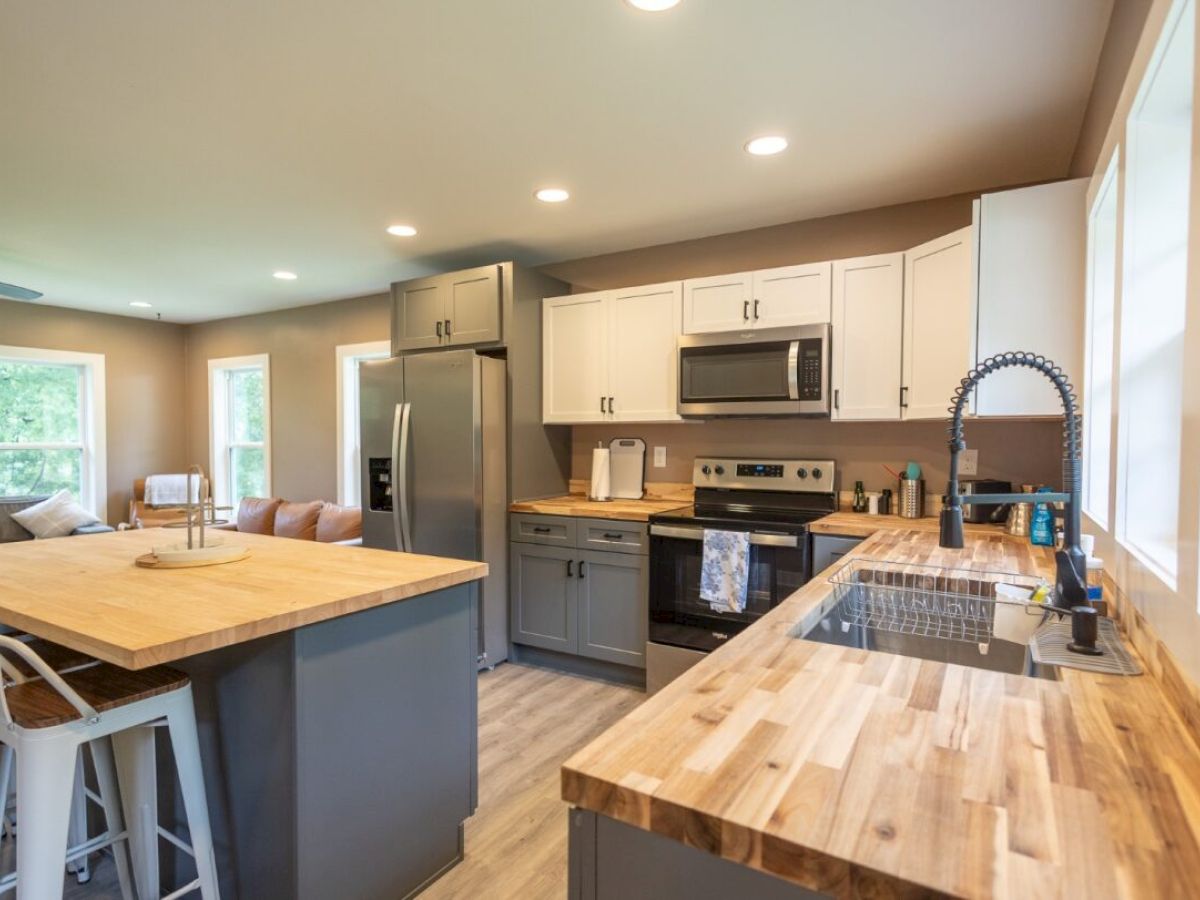 A modern kitchen with wooden countertops, stainless steel appliances, and a central island with bar stools in an open living space.